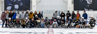 A group of PT students and volunteers/participants from Maine Adaptive post after a sled hockey demonstration at the Harold Alfond Forum