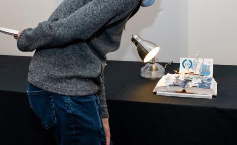 A person looks at a piece of art, which is a boat made of medical supplies